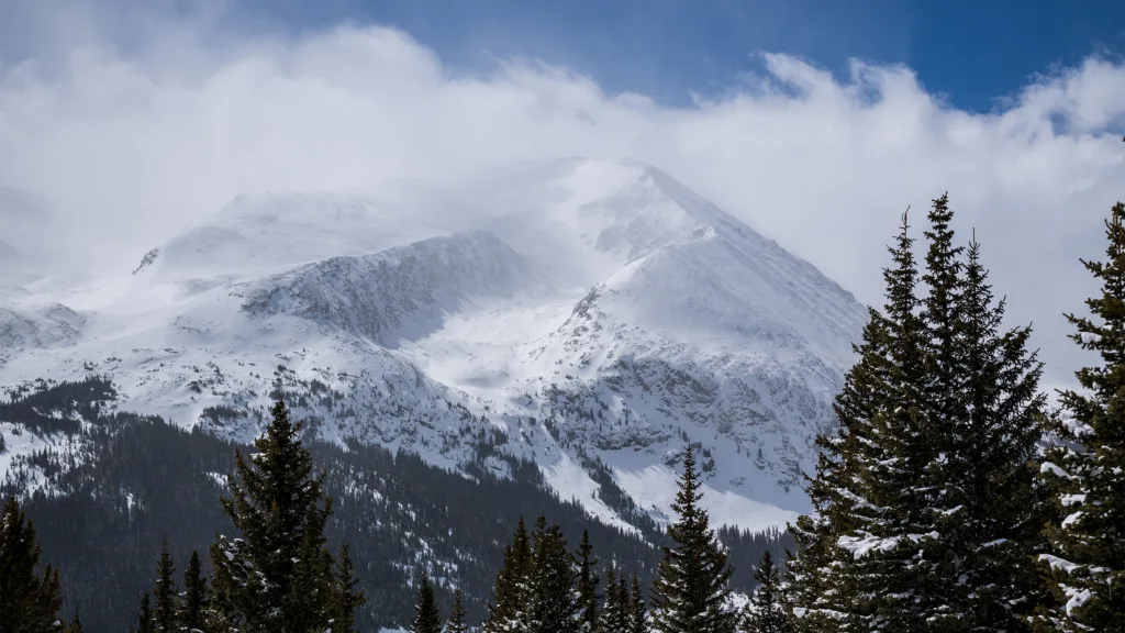 Snow blows over Colorado's Rocky Mountain range on a clear cold day. photographed with the nikon Z8 by run n gun