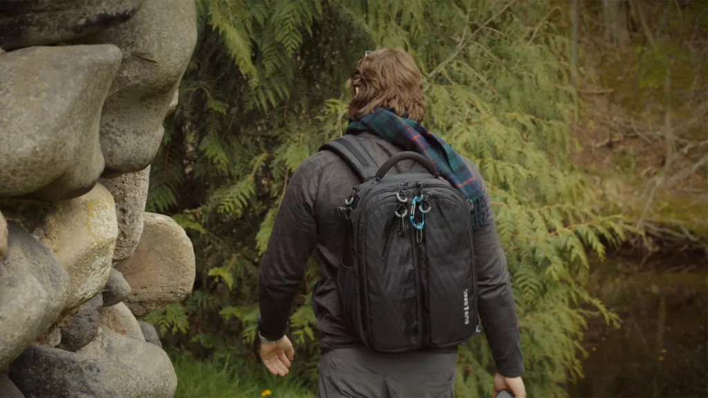 Jt walks around castle ruins in Scotland wearing a camera backpack